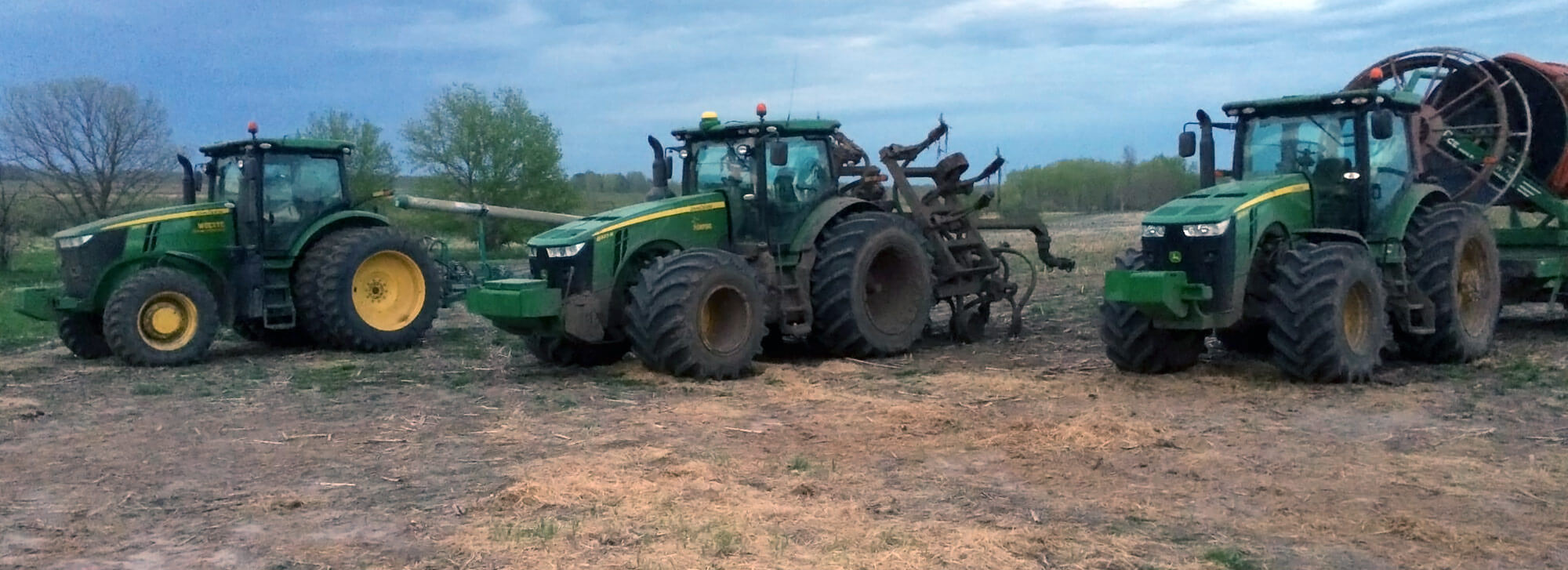 Group of John Deere tractors prepared for manure pumping via drag hose application